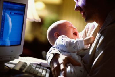 portrait of baby crying with parent by computer