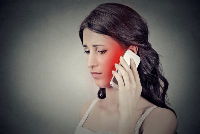 Concerned woman talking on mobile phone having headache