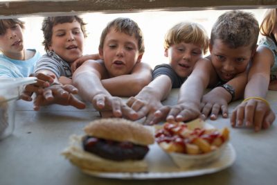 Children (6-10) at fastfood vendor's window, reaching for plate